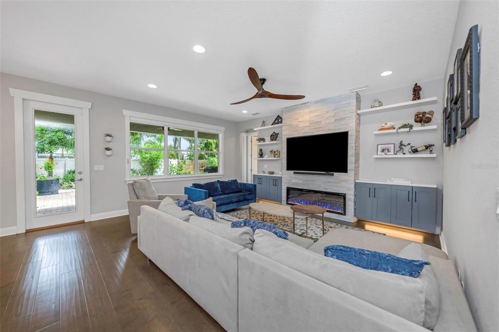 A living room features a stone fireplace, built-in shelving, a blue sofa, and hardwood floors — 4109 W VASCONIA STREET, TAMPA, FL