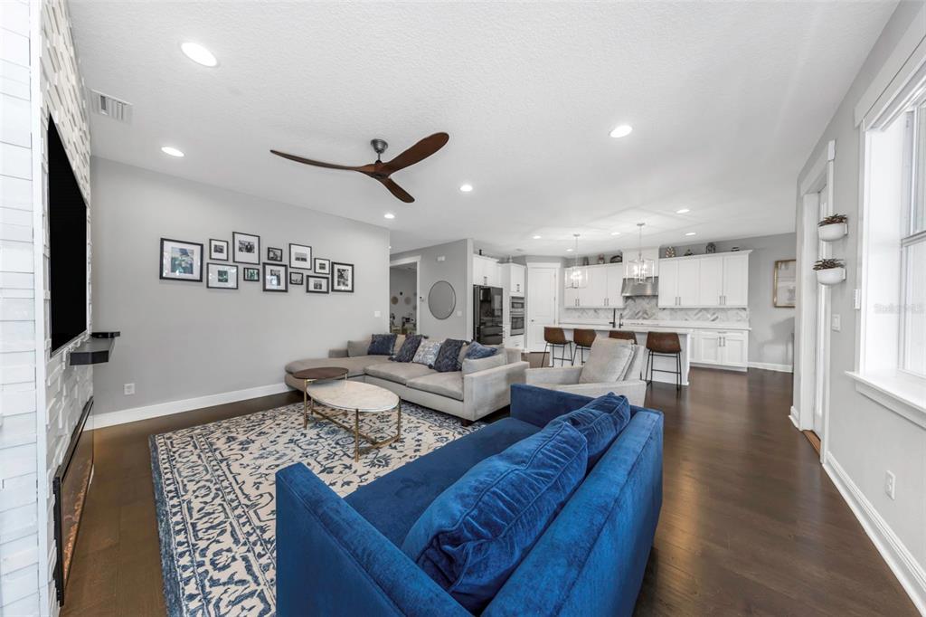 A living room with a blue sofa, gray sectional, and an open kitchen in the background — 4109 W VASCONIA STREET, TAMPA, FL