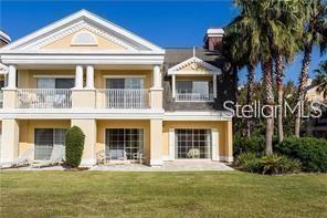 A two-story yellow building with balconies and a patio sits on a grassy lawn — 1304 SEVEN EAGLES COURT UNIT 1304, REUNION, FL