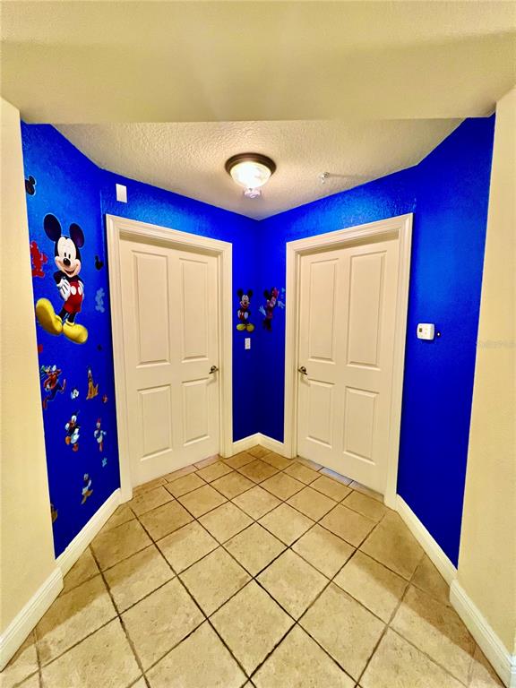 A hallway with tiled floors, blue walls decorated with Mickey Mouse decals, and two doors — 1304 SEVEN EAGLES COURT UNIT 1304, REUNION, FL