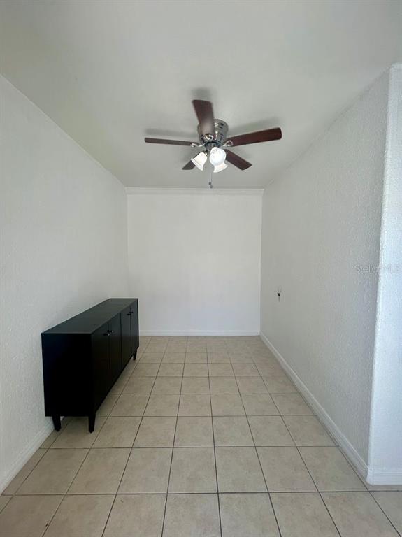 A room with white walls, tiled floors, a ceiling fan, and a black storage cabinet — 7302 WOODHALL COURT, TAMPA, FL