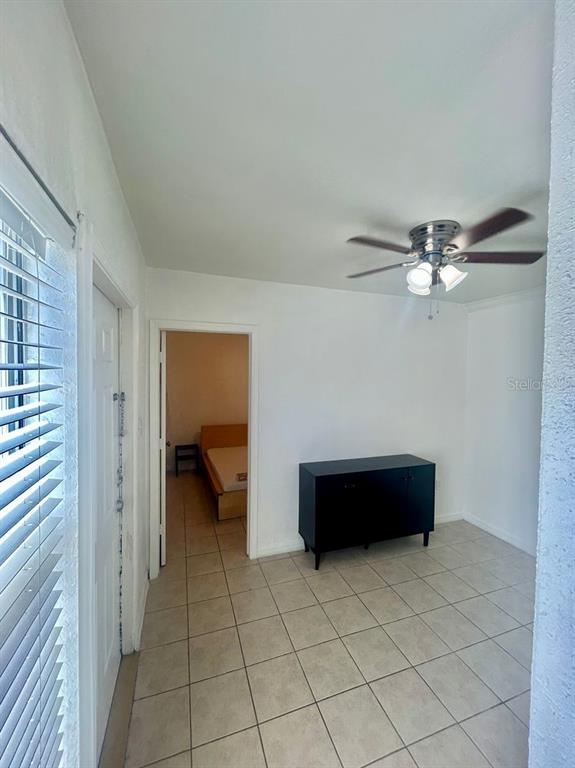 A tiled room features a ceiling fan, a black cabinet, and a doorway to a bedroom — 7302 WOODHALL COURT, TAMPA, FL