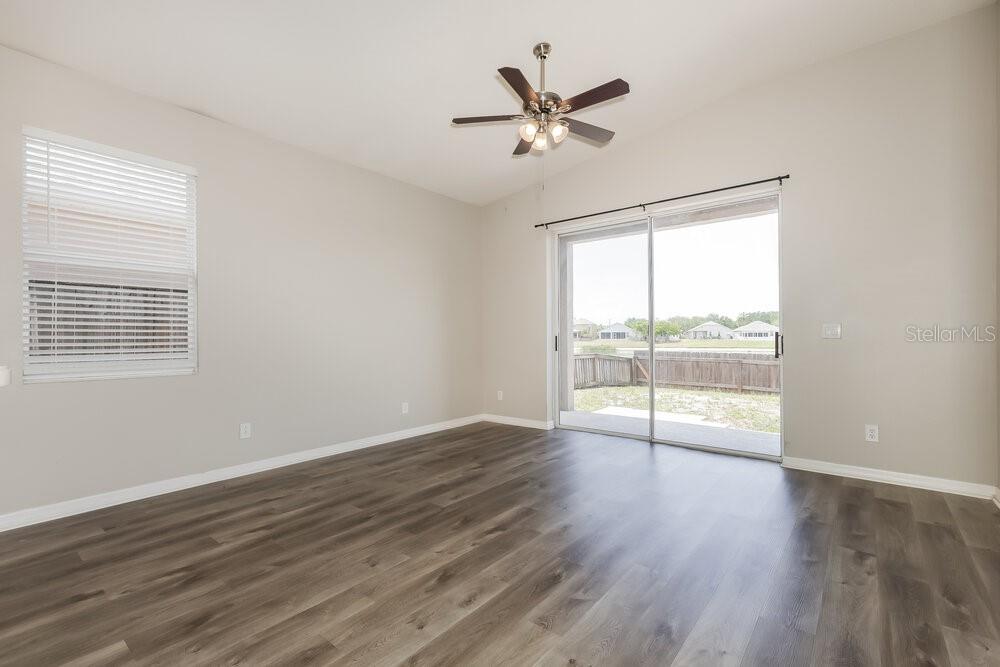 An empty room with gray wood-look flooring, a ceiling fan, and sliding glass patio doors — 5234 CLOVER MIST DRIVE, APOLLO BEACH, FL