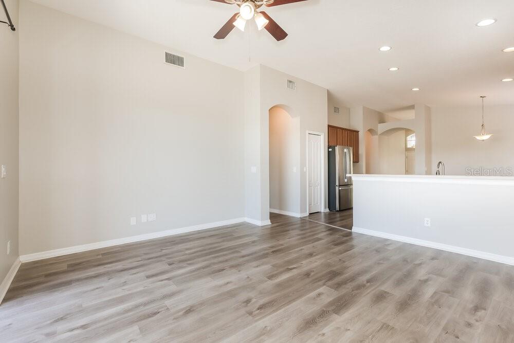 An open-concept living area features light gray wood-look flooring and a view into the kitchen — 5234 CLOVER MIST DRIVE, APOLLO BEACH, FL