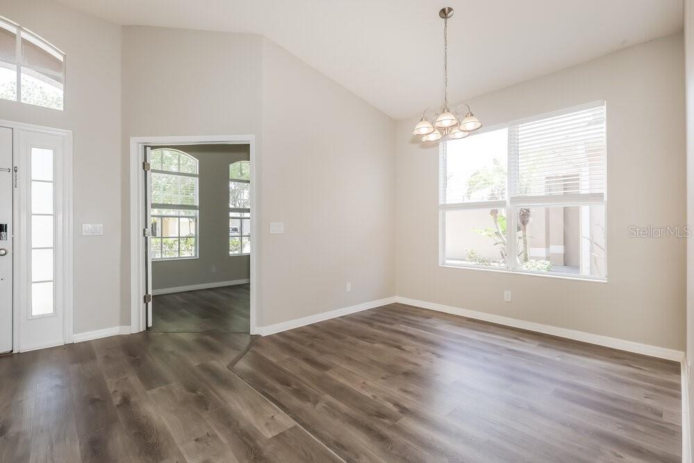 A dining area with wood-look flooring, a chandelier, and a doorway leading to another room — 5234 CLOVER MIST DRIVE, APOLLO BEACH, FL