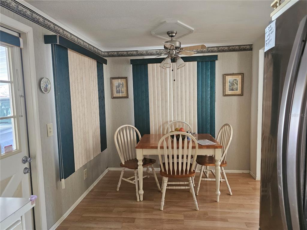 A dining area features a wooden table with four chairs, vertical blinds, and a ceiling fan — 104 IXORA WAY, LEESBURG, FL