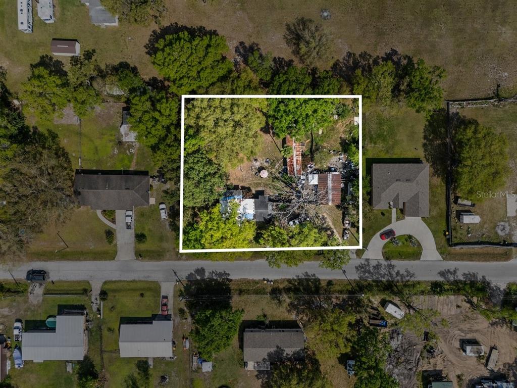 An aerial view shows a residential lot with a house and outbuildings surrounded by trees — 215 10TH WAHNETA STREET W, WINTER HAVEN, FL