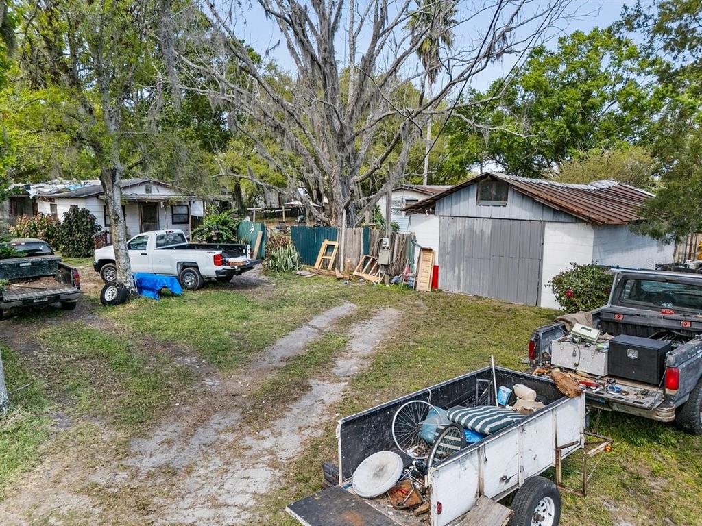 A dirt driveway leads to a house and a detached garage with two parked trucks — 215 10TH WAHNETA STREET W, WINTER HAVEN, FL