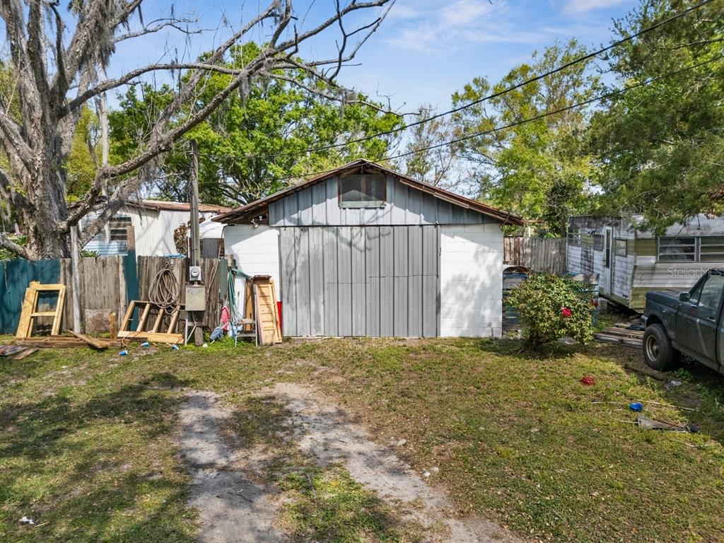 A detached garage with a metal door and white block walls sits in a grassy yard — 215 10TH WAHNETA STREET W, WINTER HAVEN, FL