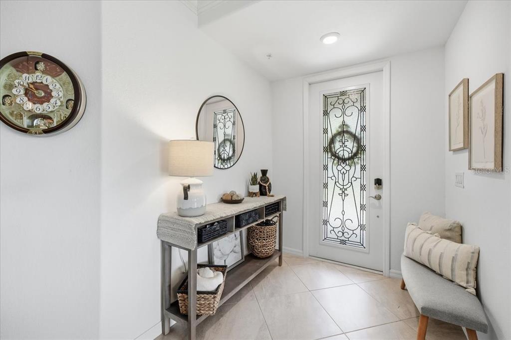 An entryway features a console table, a bench, a decorative wall clock, and a glass-paneled door — 6055 WORSHAM LANE UNIT 101, BRADENTON, FL