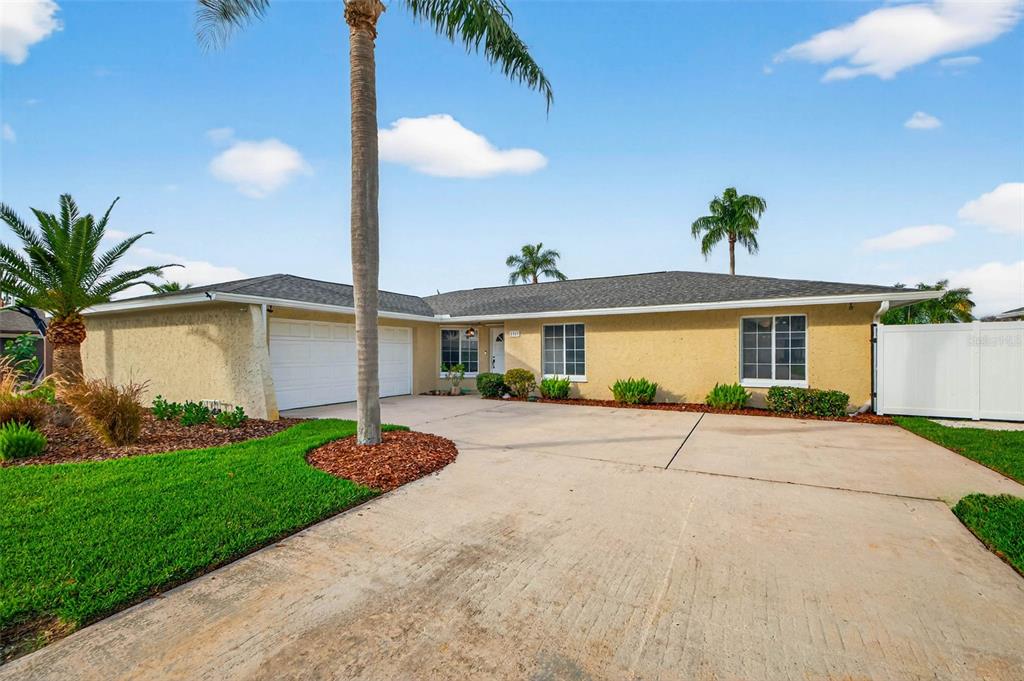 A single-story house with a two-car garage, concrete driveway, and palm trees at sunset — 1963 TANGLEWOOD DRIVE NE, ST PETERSBURG, FL