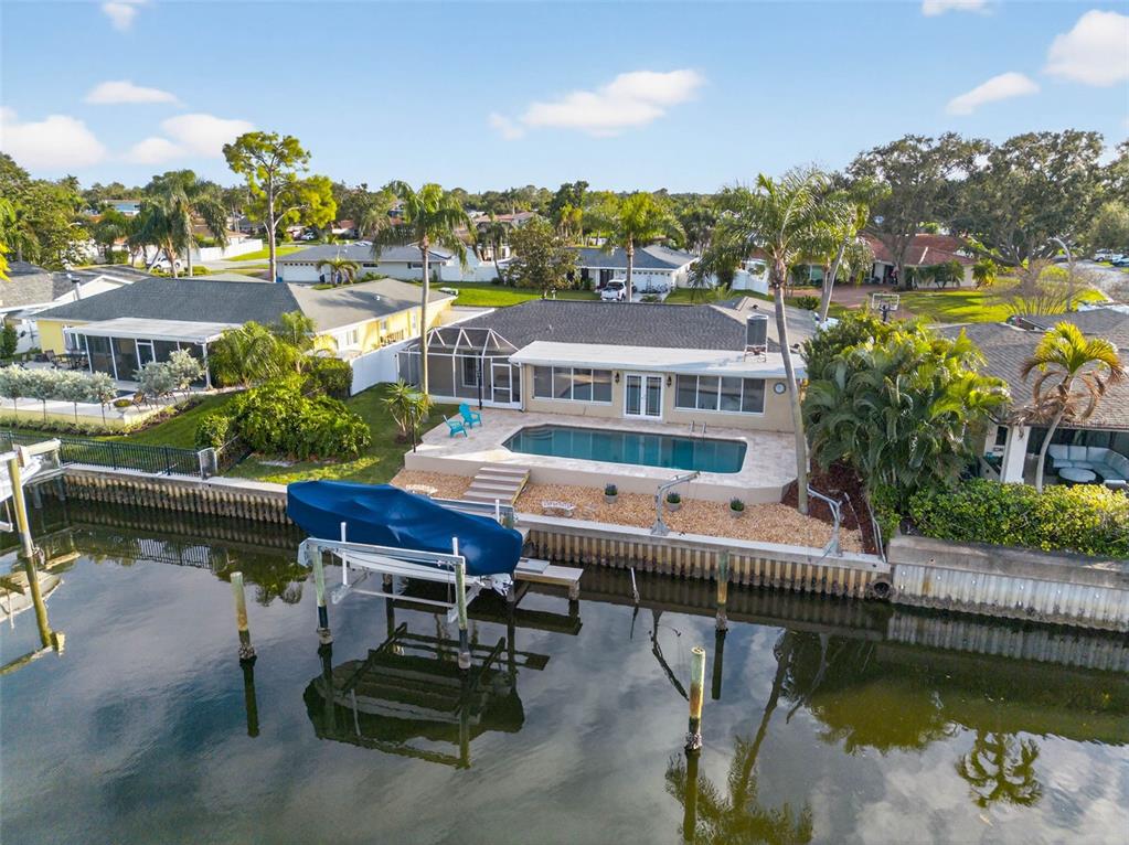 A backyard swimming pool with a stone deck overlooks a canal at sunset — 1963 TANGLEWOOD DRIVE NE, ST PETERSBURG, FL