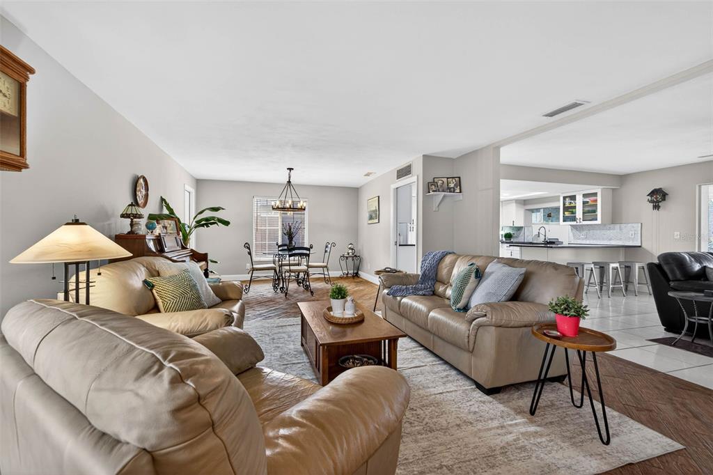 A living room with beige leather sofas, a wooden coffee table, and an adjacent dining area — 1963 TANGLEWOOD DRIVE NE, ST PETERSBURG, FL