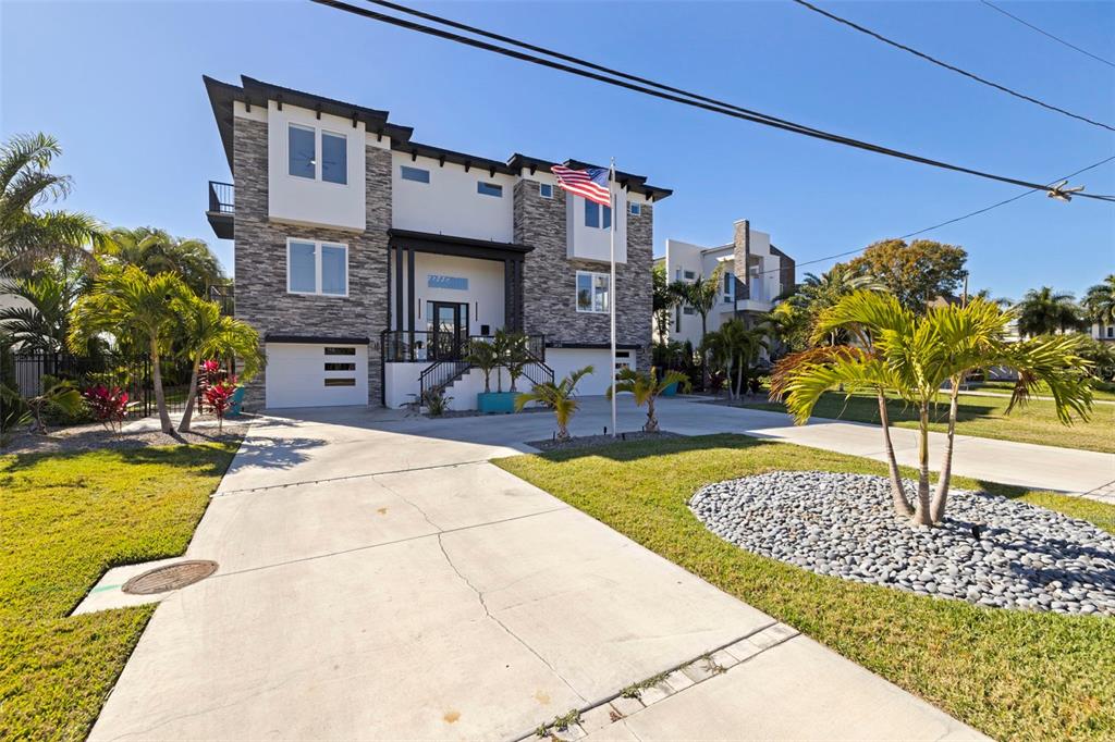 A modern three-story house with stone veneer, a white garage, and a concrete driveway — 3830 SHORE ACRES BOULEVARD NE, ST PETERSBURG, FL