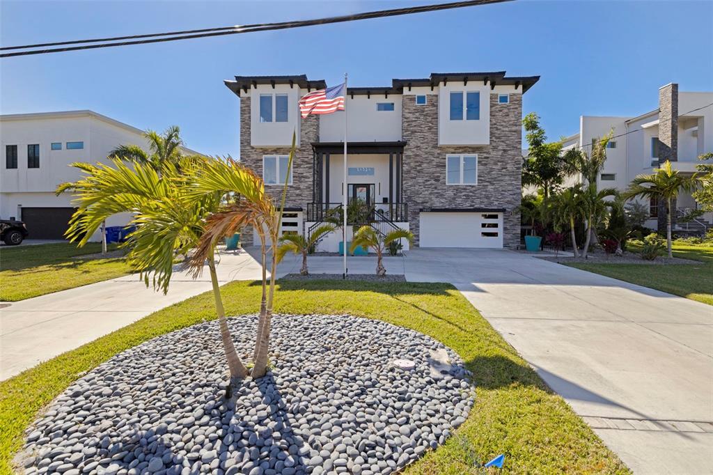 A two-story house with stone veneer, a white garage, and a palm tree in front — 3830 SHORE ACRES BOULEVARD NE, ST PETERSBURG, FL