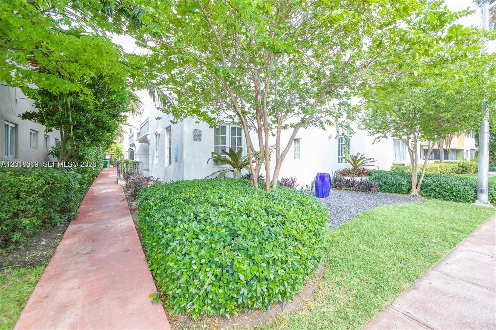 A white building exterior features a red walkway, green landscaping, and a blue decorative pot — 1508 Meridian Ave, Miami Beach FL 33139, MIAMI BEACH, FL