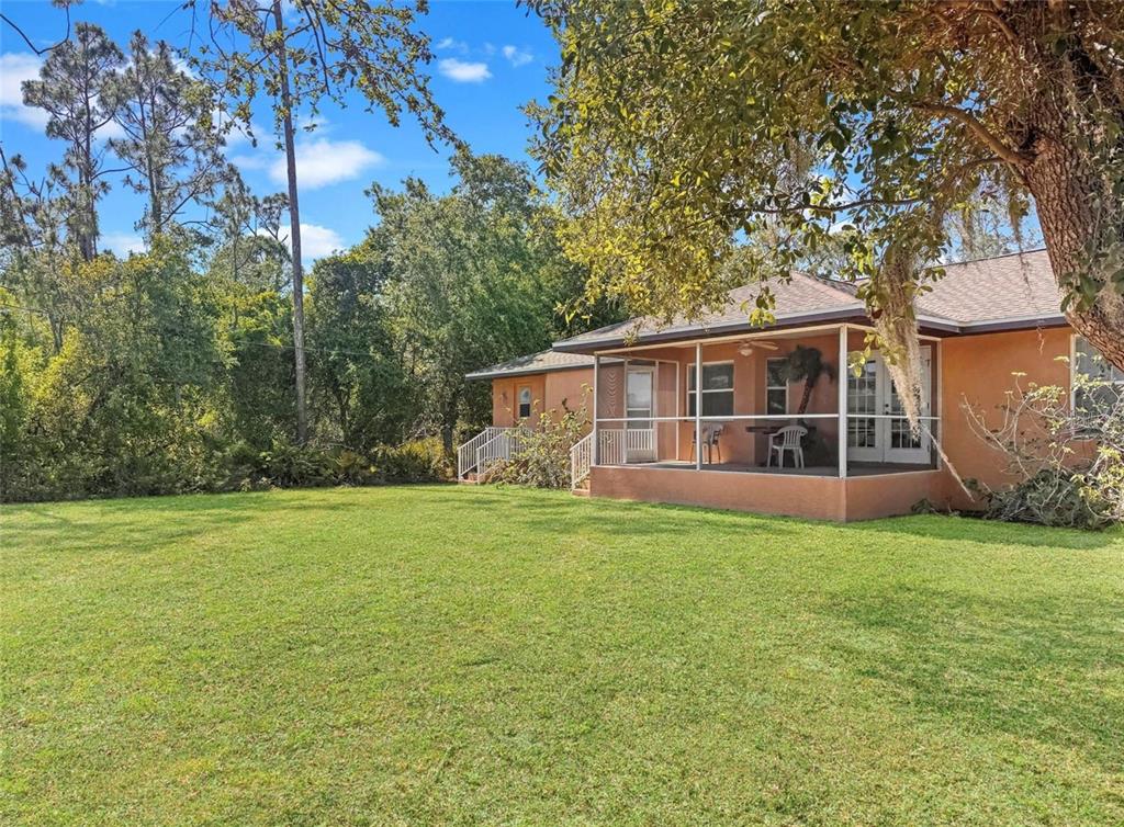 A single-story house with a screened-in porch sits beside a large, grassy lawn — 18353 GRACE AVENUE, PORT CHARLOTTE, FL