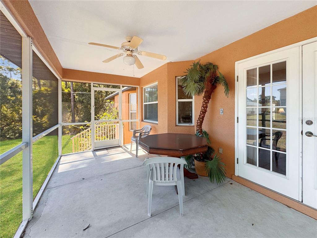 A screened-in patio features a ceiling fan, a dining table with chairs, and a palm tree — 18353 GRACE AVENUE, PORT CHARLOTTE, FL
