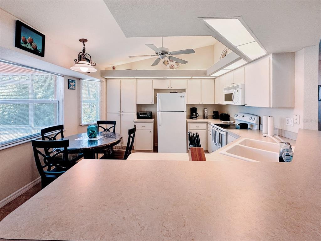A kitchen with white cabinets, a white refrigerator, and a dining area with a table — 18353 GRACE AVENUE, PORT CHARLOTTE, FL