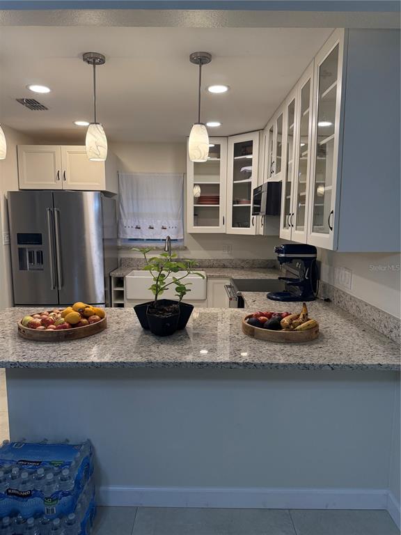 A kitchen features white cabinets, granite countertops, stainless steel appliances, and two pendant lights — 1014 VILLA LANE UNIT 7, APOPKA, FL