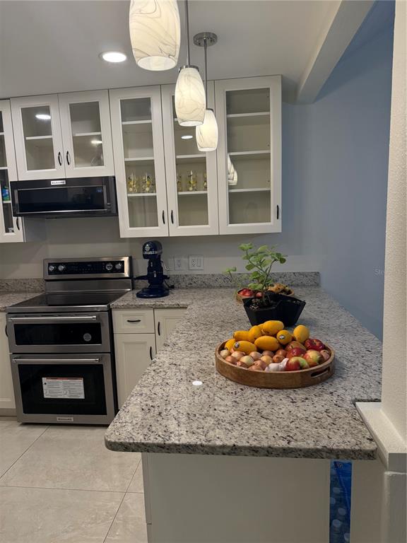 A kitchen features white cabinets, granite countertops, stainless steel appliances, and a wooden fruit bowl — 1014 VILLA LANE UNIT 7, APOPKA, FL