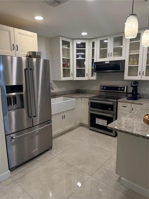 A kitchen with white cabinets, stainless steel appliances, a farmhouse sink, and granite countertops — 1014 VILLA LANE UNIT 7, APOPKA, FL