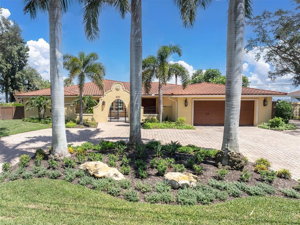 A single-story house with a tile roof, arched entryway, and a paved driveway with palm trees — 5810 BAHAMA SHORES DRIVE S, ST PETERSBURG, FL