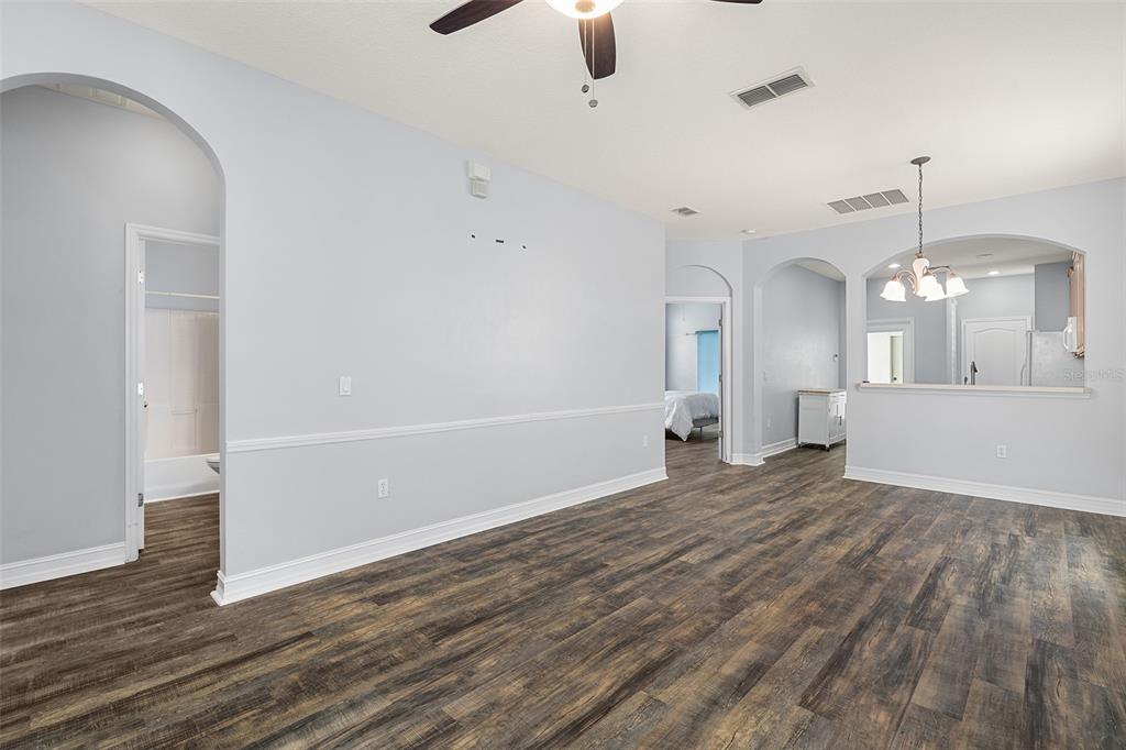 An open-concept living area features light gray walls, white trim, and dark wood-look flooring — 3333 BRACKEN FERN DR, ST CLOUD, FL