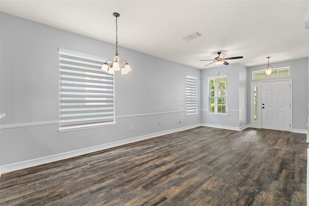 An empty room with wood-look flooring, light gray walls, a chandelier, and a front door — 3333 BRACKEN FERN DR, ST CLOUD, FL