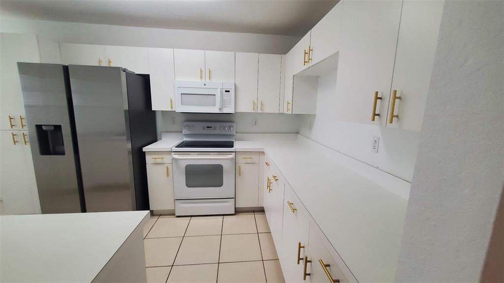 A kitchen features white cabinets, gold hardware, white countertops, and stainless steel appliances — 4176 BRENTWOOD PARK CIRCLE, TAMPA, FL