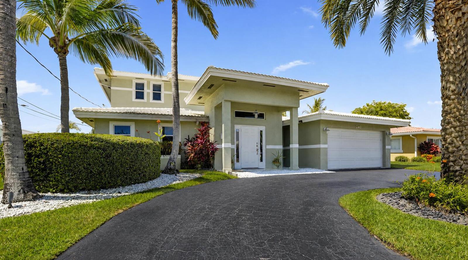 A two-story house with a white garage, a curved driveway, and palm trees in front — 240 SE 3rd Court, Pompano Beach FL 33060, POMPANO BEACH, FL