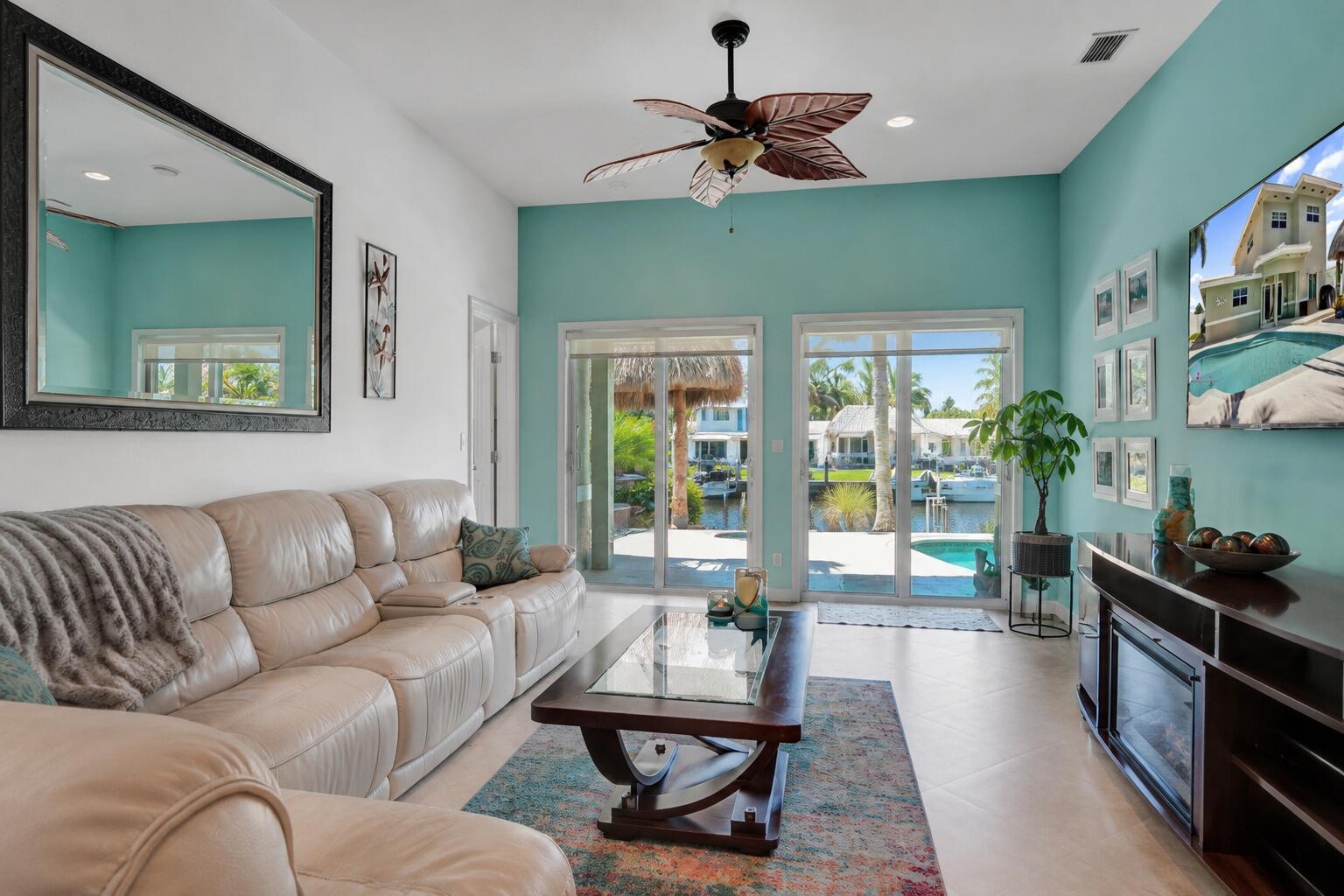 A living room features a beige leather sofa, glass coffee table, and views of a canal — 240 SE 3rd Court, Pompano Beach FL 33060, POMPANO BEACH, FL
