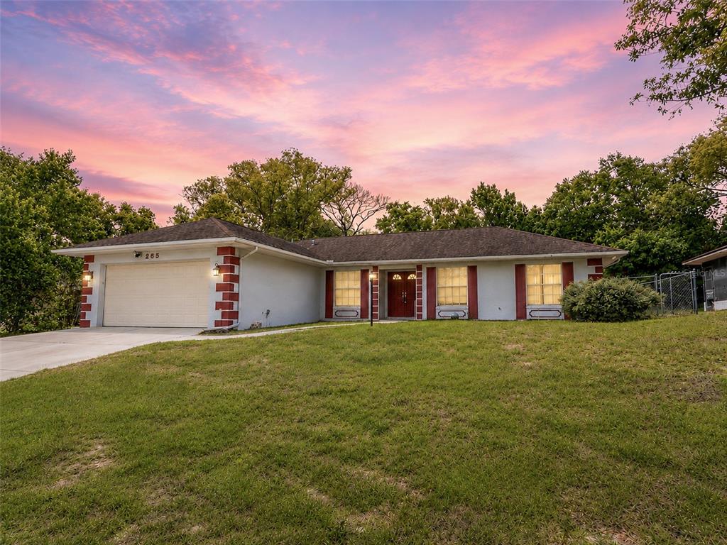 A single-story house with a white exterior, red brick accents, and a two-car garage — 265 CLEARFIELD AVENUE, SPRING HILL, FL