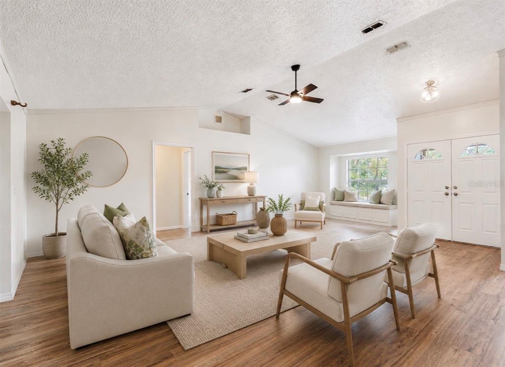A bright living room features light wood flooring, a vaulted ceiling, and a window seat — 265 CLEARFIELD AVENUE, SPRING HILL, FL