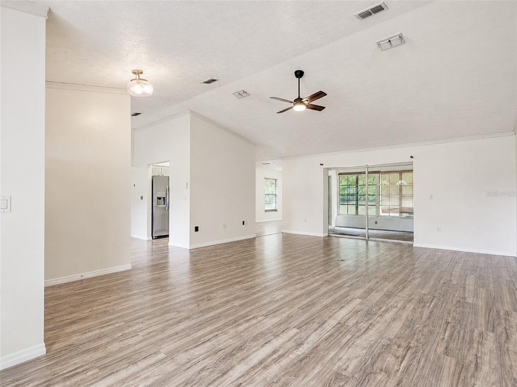 An open-concept living area features light wood-look flooring, white walls, and a ceiling fan — 265 CLEARFIELD AVENUE, SPRING HILL, FL
