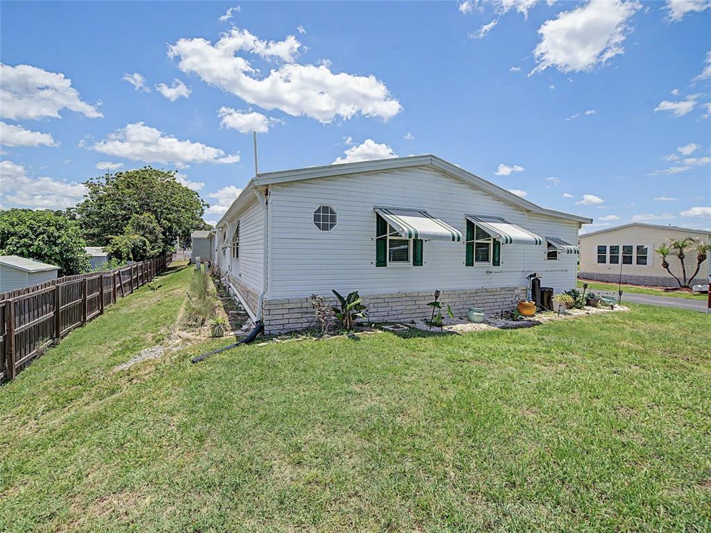 A white mobile home with green-striped window awnings sits on a grassy lot — 37513 CAMPO AVENUE, ZEPHYRHILLS, FL