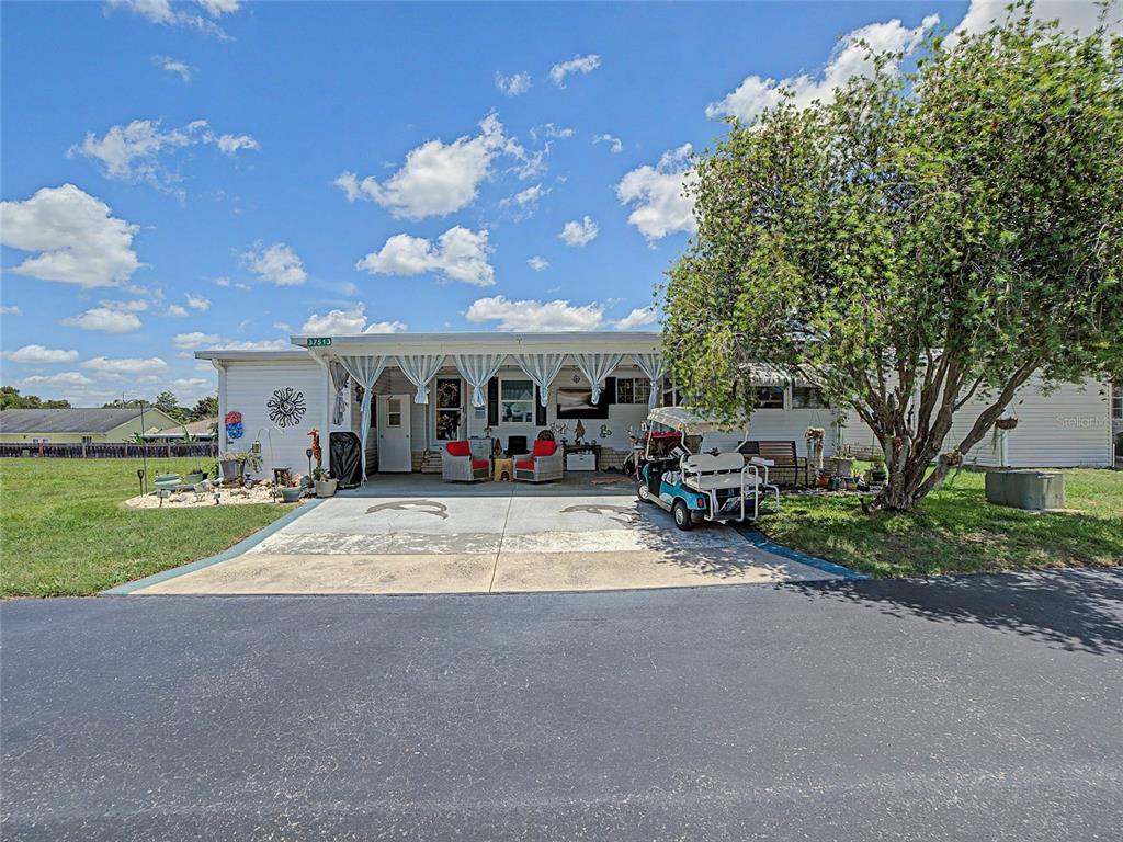 A single-story manufactured home features a covered carport, a golf cart, and a front patio — 37513 CAMPO AVENUE, ZEPHYRHILLS, FL