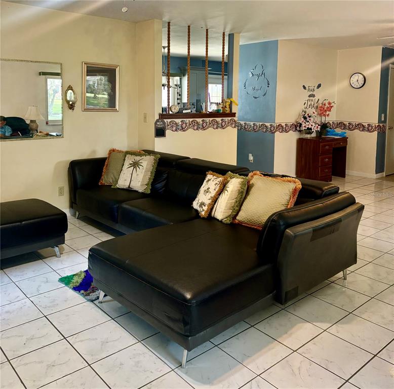 A living room features a black sectional sofa, tiled floors, and a decorative room divider — 107 E PALM STREET, DAVENPORT, FL