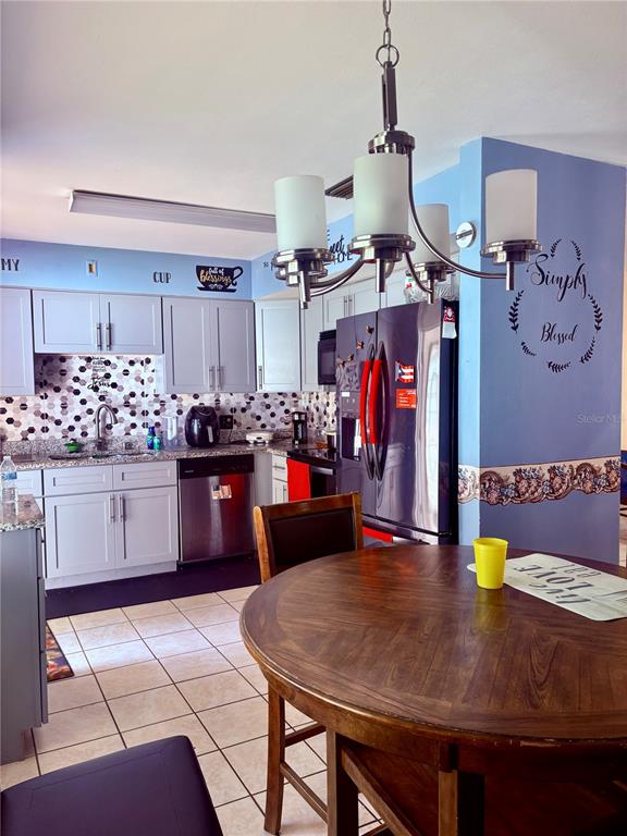 A kitchen with gray cabinets, a dark refrigerator, and a round wooden dining table — 107 E PALM STREET, DAVENPORT, FL
