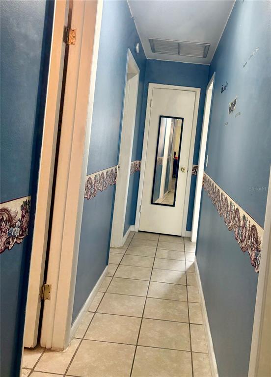 A hallway with blue walls, decorative wallpaper borders, and light-colored square floor tiles — 107 E PALM STREET, DAVENPORT, FL