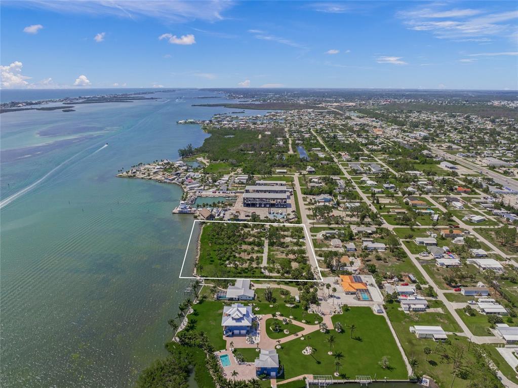 An aerial view shows a vacant waterfront lot outlined in white near a coastal neighborhood — 1 RASCHE ROAD, ENGLEWOOD, FL