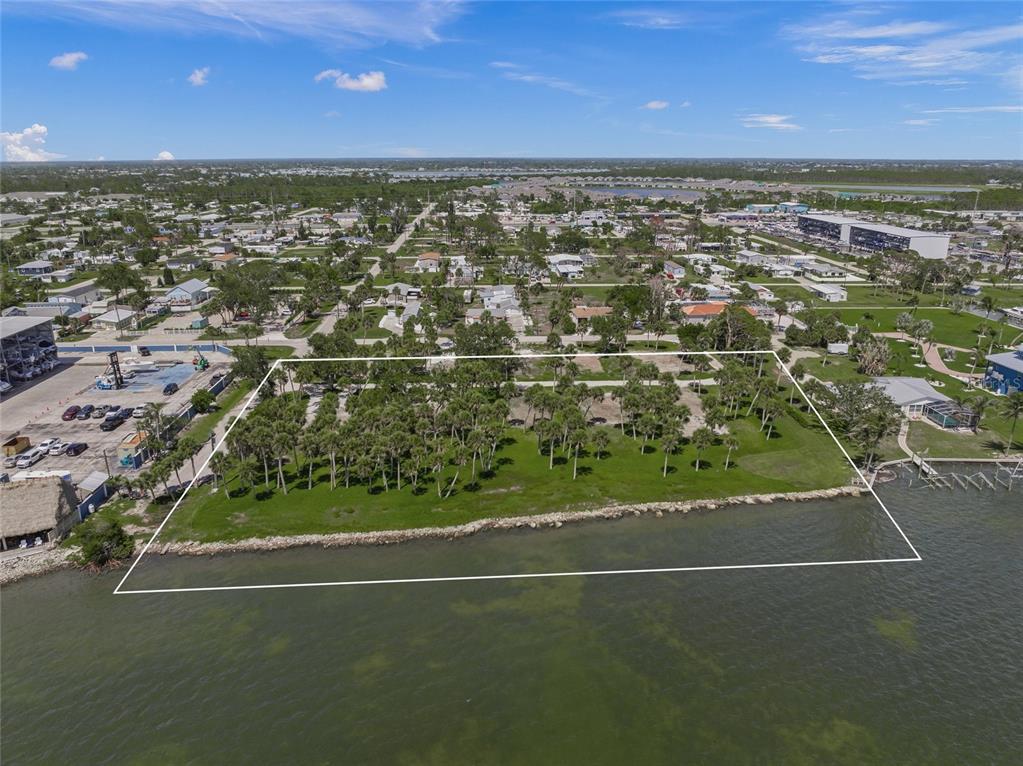 An aerial view shows a rectangular waterfront lot with palm trees and a rocky shoreline — 1 RASCHE ROAD, ENGLEWOOD, FL