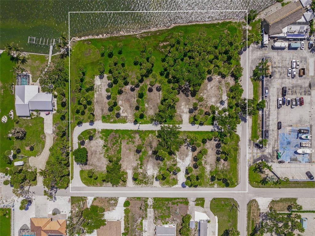 An aerial view shows a vacant, partially wooded waterfront lot outlined in white — 1 RASCHE ROAD, ENGLEWOOD, FL