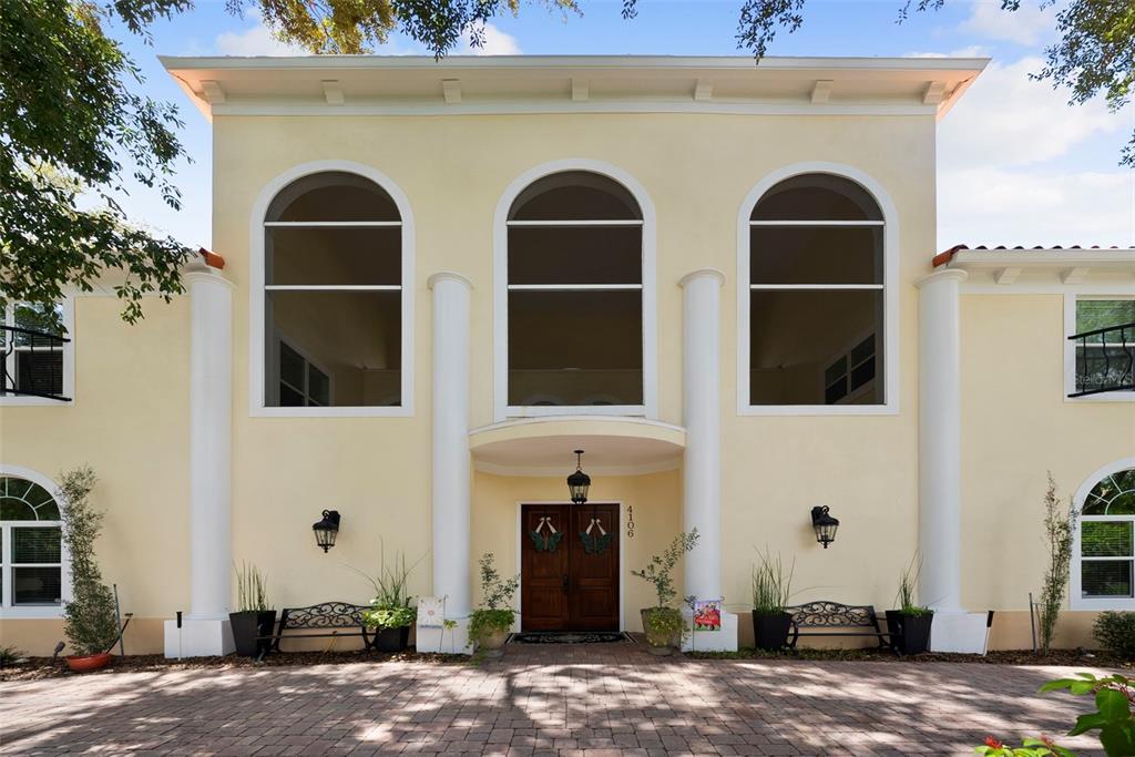 A two-story yellow stucco house with a brick driveway and arched windows — 4106 W SAN MIGUEL STREET, TAMPA, FL