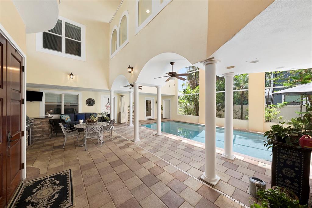 A covered patio features a swimming pool, tiled flooring, white columns, and a dining area — 4106 W SAN MIGUEL STREET, TAMPA, FL