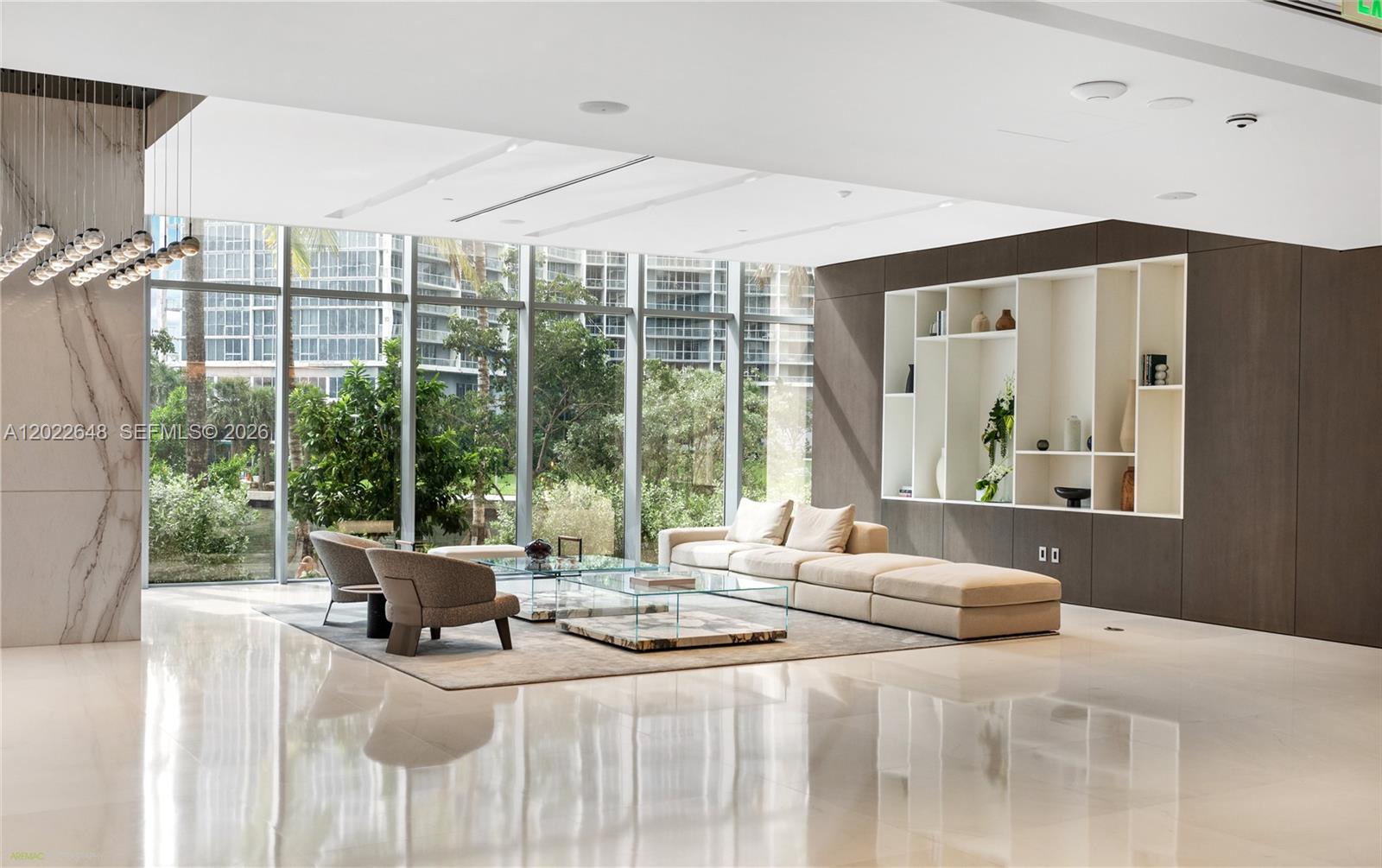 A modern living room features floor-to-ceiling windows, a large beige sectional, and built-in shelving — 300 Biscayne Blvd Way # 3604, Miami FL 33131, MIAMI, FL