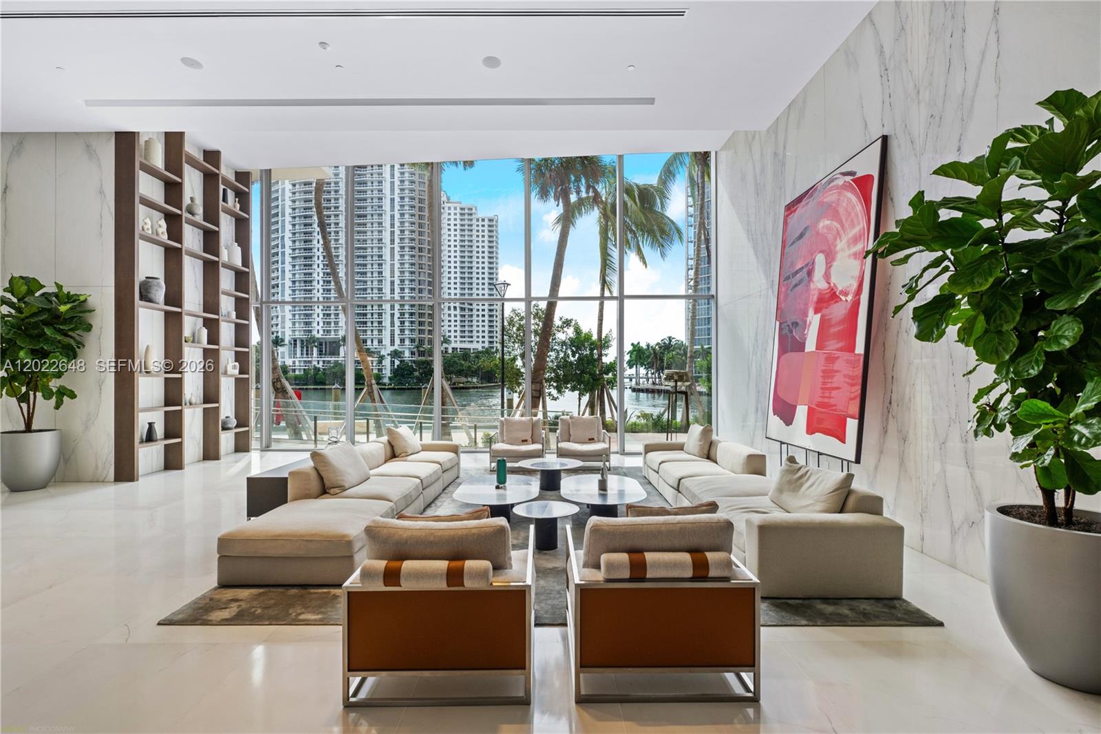 A spacious living room features floor-to-ceiling windows, marble walls, large sofas, and indoor plants — 300 Biscayne Blvd Way # 3604, Miami FL 33131, MIAMI, FL