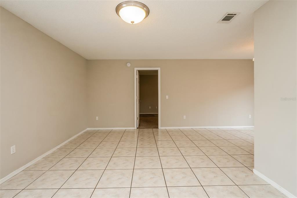 An empty room with beige walls, a tiled floor, and a central doorway — 2680 SWEET SPRINGS STREET, DELTONA, FL