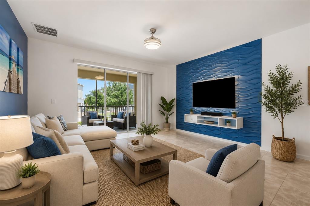 A living room features a blue textured accent wall, a television, and a sectional sofa — 8895 CABOT CLIFFS DRIVE UNIT 103, DAVENPORT, FL