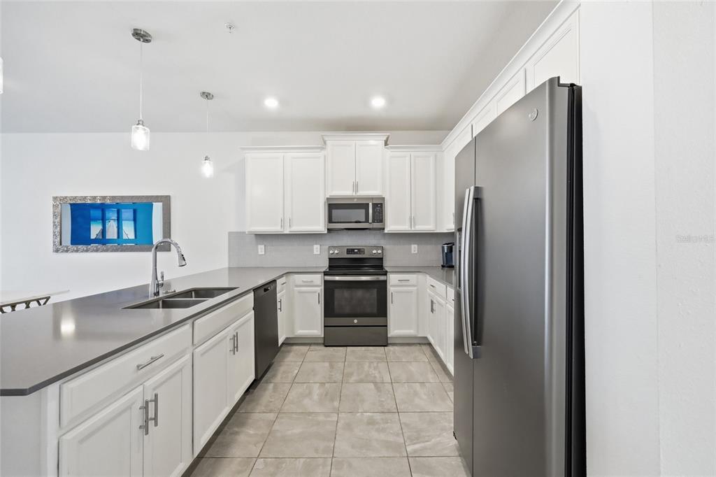 A kitchen with white cabinets, dark countertops, stainless steel appliances, and tile flooring — 8895 CABOT CLIFFS DRIVE UNIT 103, DAVENPORT, FL